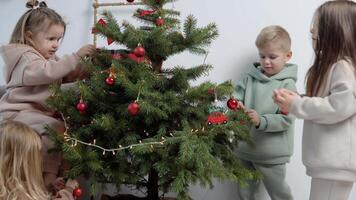 dulce niños en elegante casual trajes Decorar un Navidad árbol video