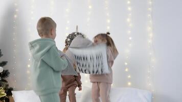 Children jumping on the bed with pillows near Christmas decorations video