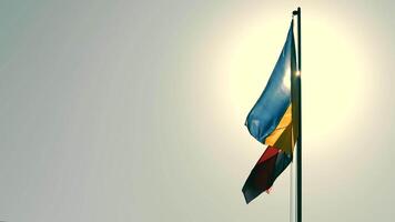 Silhouette of the flag of Ukraine and the Flag of the Ukrainian Insurgent Army. Contrast sun rays illuminate the silhouette of the flags against the background of the blue sky video