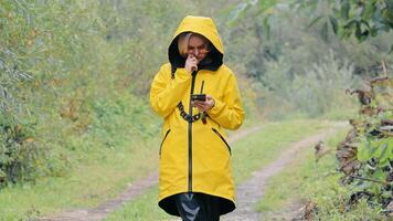 A woman tourist got lost in the forest and is looking at a map on her phone. Tourists are ready in the forest. Lonely woman in the forest video