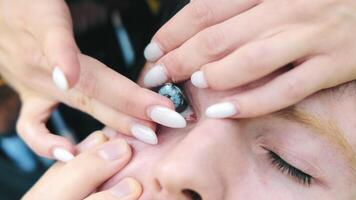 Contact lenses are put on a man's eye with a blue pupil. Close-up of a woman's fingers putting on a man's contact lenses. video