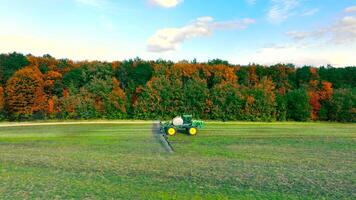 Aerial view A tractor plows the field and waters the young wheat. Growing wheat in the field. Wheat care. Spring work in the field video