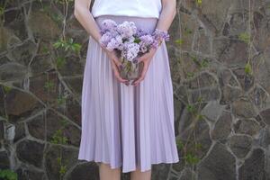 Woman is holding a vase with bouquet of lilac close up. photo