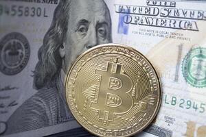 dorado bitcoin y dolares en masculino mano en un oscuro azul de madera antecedentes. oro moneda de criptomoneda foto