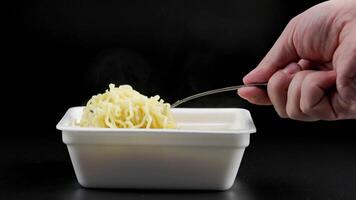 hand with fork stirring cooked instant noodles from styrofoam container video