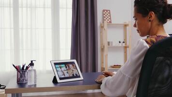 Woman listening her colleagues during a video call on tablet computer from home office.