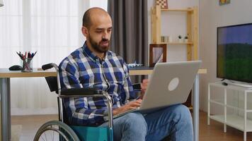 Invalid freelancer in wheelchair working remotely on laptop. video