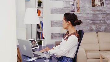 mulher dentro uma vídeo ligar em tábua computador digitando em computador portátil enquanto trabalhando a partir de lar. video
