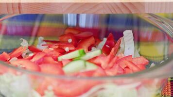 woman add chopped cucumber into bowl with cut chinese cabbage and bell pepper video