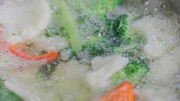 spoon stirring and removing scum foam out from boiling broccoli, cauliflower and red bell pepper video