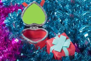 Heart shaped jewelry box and red gift box on tinsel background with copy space for text. photo