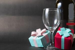 Wine bottle and two gift boxes on black background. Valentine's day concept photo