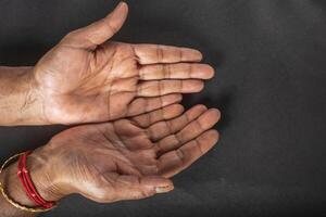 Close up of a senior woman's open hands on a black background. Conceptual photo. photo