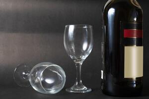 Bottle of red wine and two empty wine glasses on a black background photo