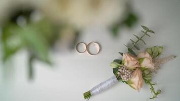 Wedding boutonniere and wedding rings on brown cloth. Wedding rings and boutonniere photo