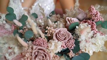 The bride holds a beautiful wedding bouquet of pink and white flowers in her hands. Beautiful wedding bouquet in the hands of the bride. photo