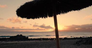 en se av en solnedgång strand genom strand stol och paraply video