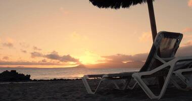 ein Aussicht von ein Sonnenuntergang Strand durch Strand Stuhl und Regenschirm video