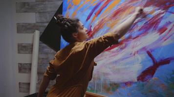 Artist using paint brush on large canvas in studio making abstract art. video