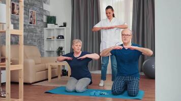 senior paar aan het doen fysiek behandeling met dokter Bij huis. huis bijstand, fysiotherapie, gezond levensstijl voor oud persoon, opleiding en gezond levensstijl video