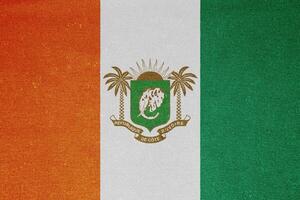 Flag and coat of arms of Republic of Cote d'Ivoire on a textured background. Concept collage. photo