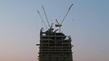 silhouet van bouw werf van een wolkenkrabber in de stad met kranen video