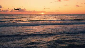 silueta de avión tomar apagado en el Oceano a puesta de sol video