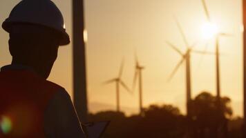 Silhouette of an engineer inside a wind farm at sunset video