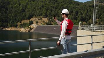 Architect taking photo with smartphone an artificial dam on the mountains video