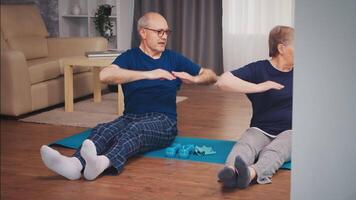 vreugdevol senior paar aan het doen fysiek opleiding in leven kamer. oud persoon gezond levensstijl oefening Bij huis, training en opleiding, sport werkzaamheid Bij huis video