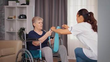 Sénior femme dans fauteuil roulant Faire réhabilitation traitement avec assistance de infirmière. entraînement, sport, récupération et levage, vieux la personne retraite maison, soins de santé allaitement, santé soutien, social assistance, médecin et Accueil un service video