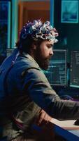 verticaal video ingenieur met eeg koptelefoon invoegen patroon in pc naar gebruik hoog tech software toelaten voor hersenen overdracht in virtueel wereld. Mens zetten schijf in computer naar begin bewustzijn uploaden, camera b