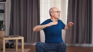 Alten Mann ausüben im Leben Zimmer Sitzung auf Stabilität Ball. alt Person Rentner gesund Ausbildung Gesundheitswesen Sport beim heim, ausüben Fitness Aktivität beim Alten Alter video