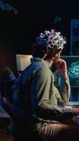 Vertical video IT expert using EEG headset and machine learning to upload brain into computer, gaining immortality. Computer scientist develops AI experiment, inserting his persona into cyberspace, camera B