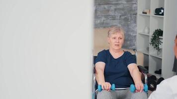 Senior Frau im Rollstuhl tun Zuhause Rehabilitation Ausbildung mit Arzt. deaktiviert behindert alt Person erholen Fachmann Hilfe Krankenschwester, Pflege- Pensionierung Zuhause Behandlung und Rehabilitation video