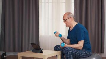 anziano uomo godendo Lavorando su con manubri durante in linea fitness programma. vecchio persona pensionato salutare formazione assistenza sanitaria sport a casa, esercizio fitness attività a anziano età video