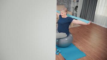 heiter Senior Frau ausüben auf Balance Ball. alt Person Ausbildung beim Zuhause Sport gesund Lebensstil, Alten Fitness Übung trainieren im Wohnung, Aktivität und Gesundheitswesen video