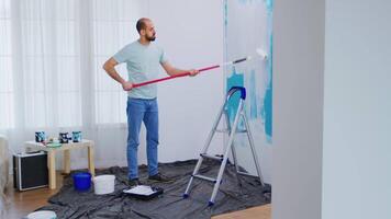 Masaking blue paint with roller brush dipped in white paint. Handyman renovating. Apartment redecoration and home construction while renovating and improving. Repair and decorating. video