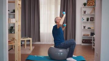 Sénior homme avec vitalité exercice en utilisant haltères dans vivant chambre. vieux la personne retraité en bonne santé formation soins de santé sport à maison, exercice aptitude activité à personnes âgées âge video