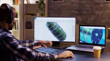 Side view of engineer wearing headphones and working on a turbine using modern software for design. video