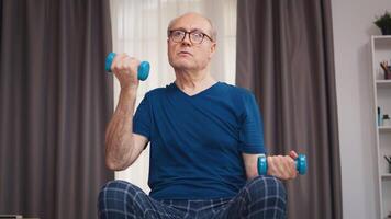 Elderly man training biceps in living room. Old person pensioner healthy training healthcare sport at home, exercising fitness activity at elderly age video