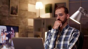 uomo d'affari pensiero e Tenere braccia attraversato mentre Lavorando su il computer portatile nel casa ufficio durante notte ore. video