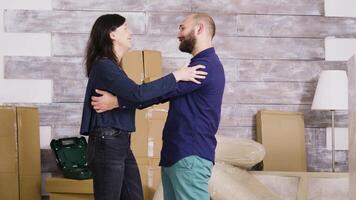 content Jeune couple étreindre chaque autre dans leur Nouveau appartement. papier carton des boites dans le Contexte. video