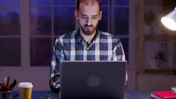 Pensive businessman looking into his laptop during night hours in home office. video