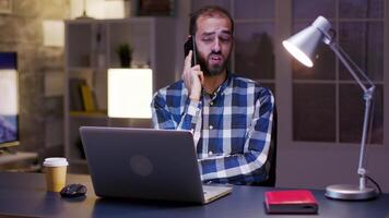 Young entrepreneur yawn while having a conversation on the phone. Businessman working overtime. video