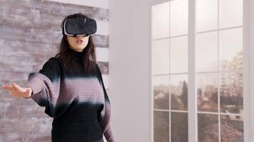 lindo fêmea casa desenhador usando virtual realidade óculos dentro do a esvaziar apartamento. video