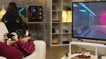 Woman using vr headset to play video games and wireless controller lying on sofa.