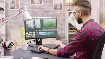 Creative filmmaker working on post production of a movie while working from home. Girlfriend in the background is walking in the house and talking on the phone. video