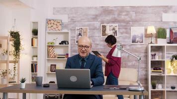 gelukkig oud Mens na lezing een mooi zo nieuws Aan laptop. vrouw gebruik makend van tablet in de achtergrond. video