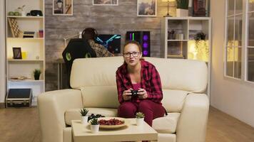 jung Frau aufgeregt nach ihr Sieg während spielen Video Spiele im Leben Zimmer mit kabellos Regler. Freund im das Hintergrund.